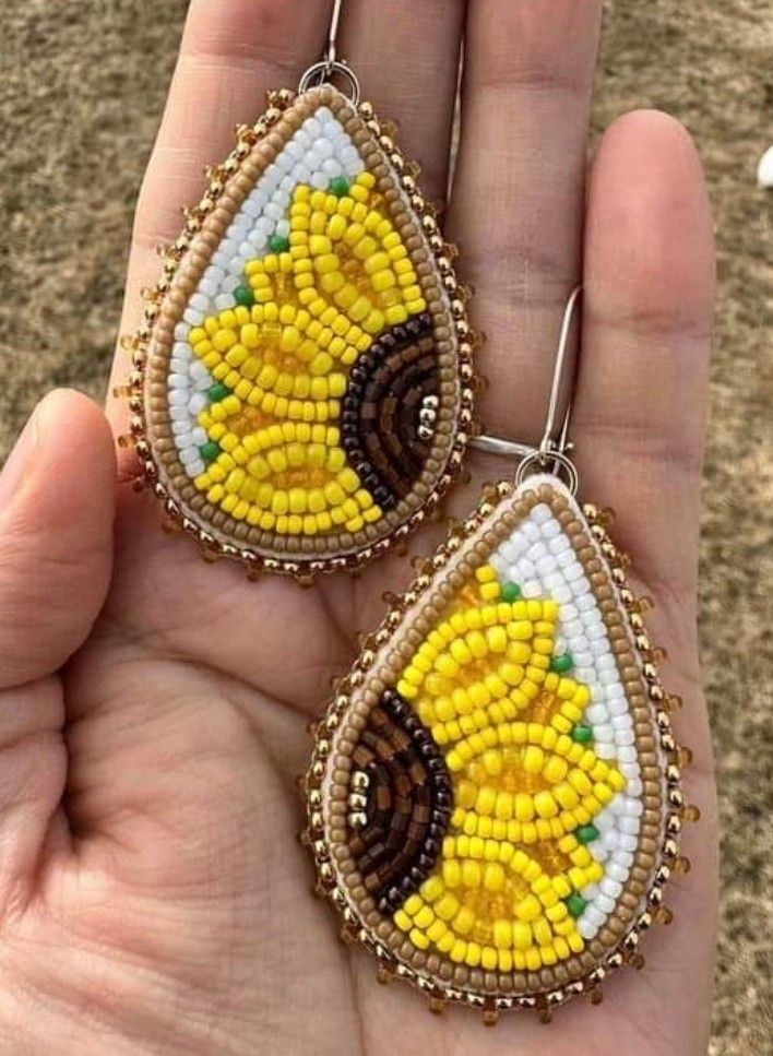 a pair of yellow and white beaded earrings with sunflowers on the inside