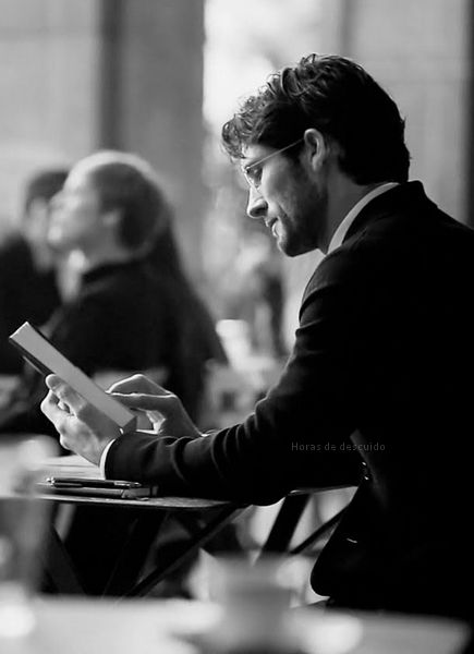 a man sitting at a table in front of a woman holding a book and looking at something