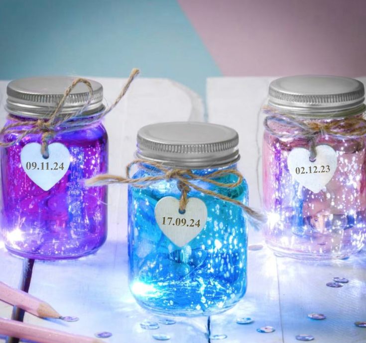 three mason jars filled with blue, purple and pink liquid sitting on top of a table