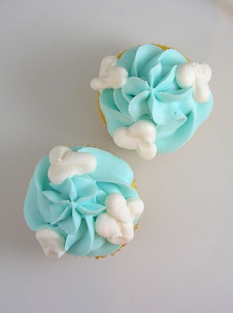 two cupcakes with blue frosting and white decorations