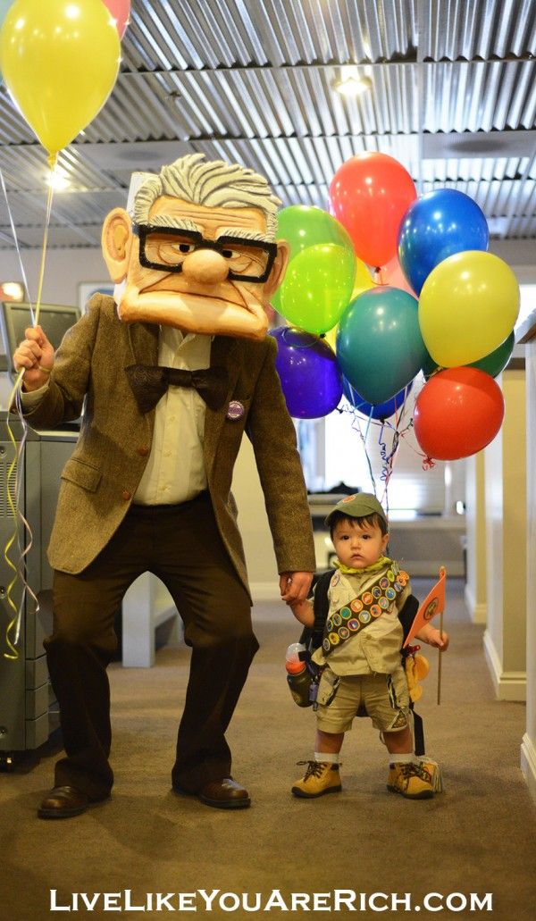 a man in a suit and tie standing next to a little boy with balloons on his head