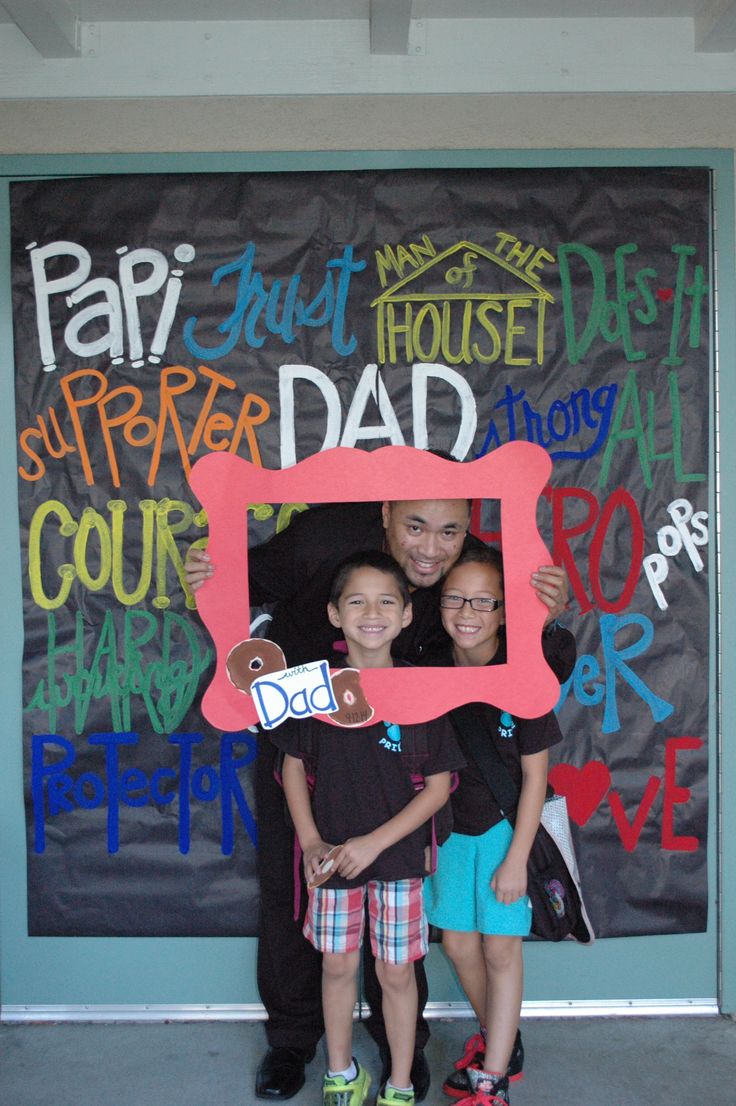 two children and an adult posing in front of a chalk board with the word dad written on it