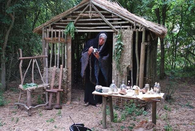 a man standing in front of a wooden structure with pottery on it's table