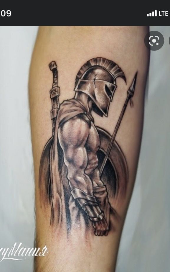 a man's arm with a spartan tattoo on it