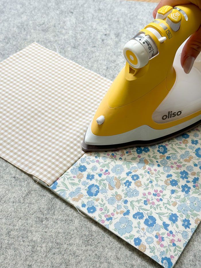 a person ironing fabric with an electric iron on top of the cloth next to it