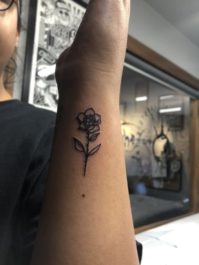 a woman's arm with a small rose tattoo on it