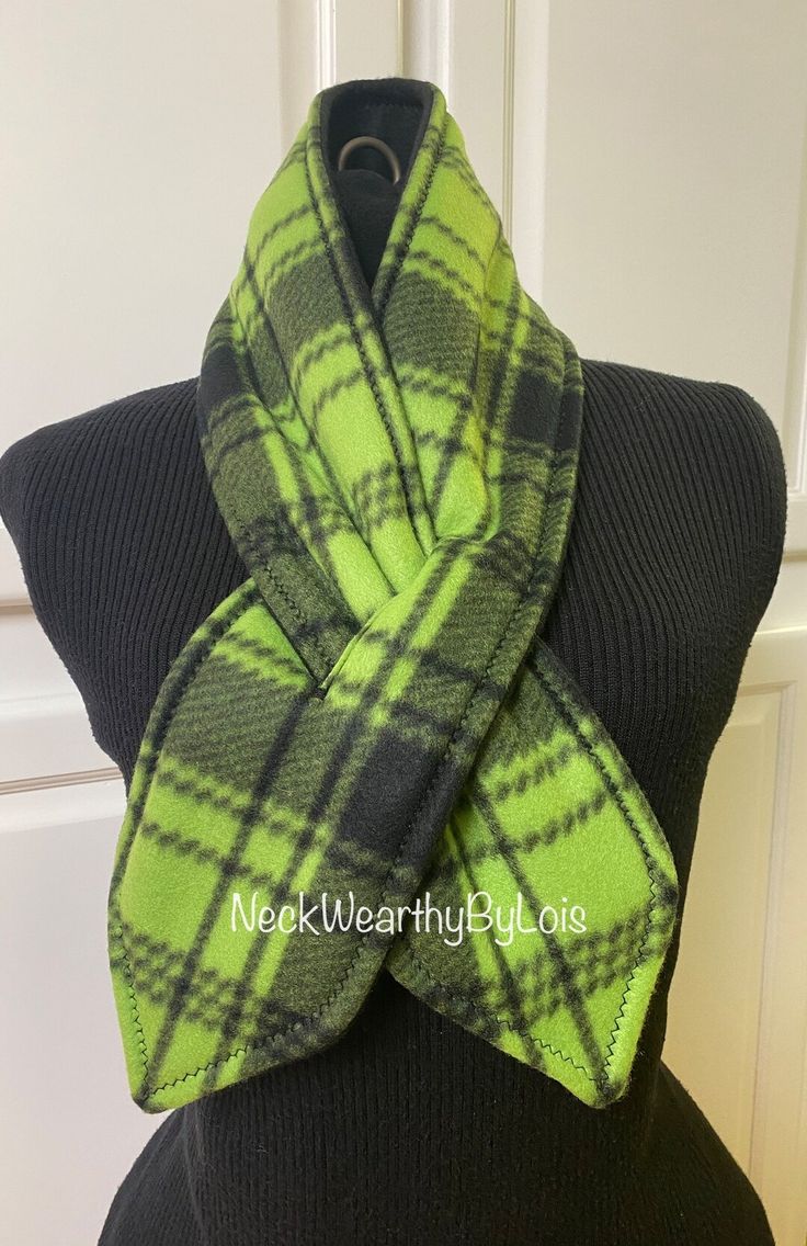 a green and black plaid scarf on top of a mannequin