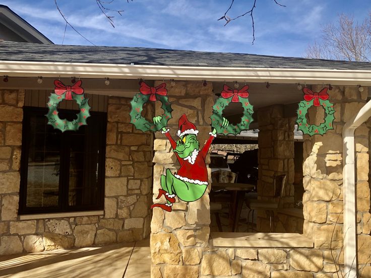 a house decorated for christmas with the grino on it's front porch and wreaths