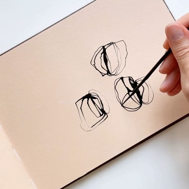 a person is holding a pencil and drawing something with black ink on a piece of paper