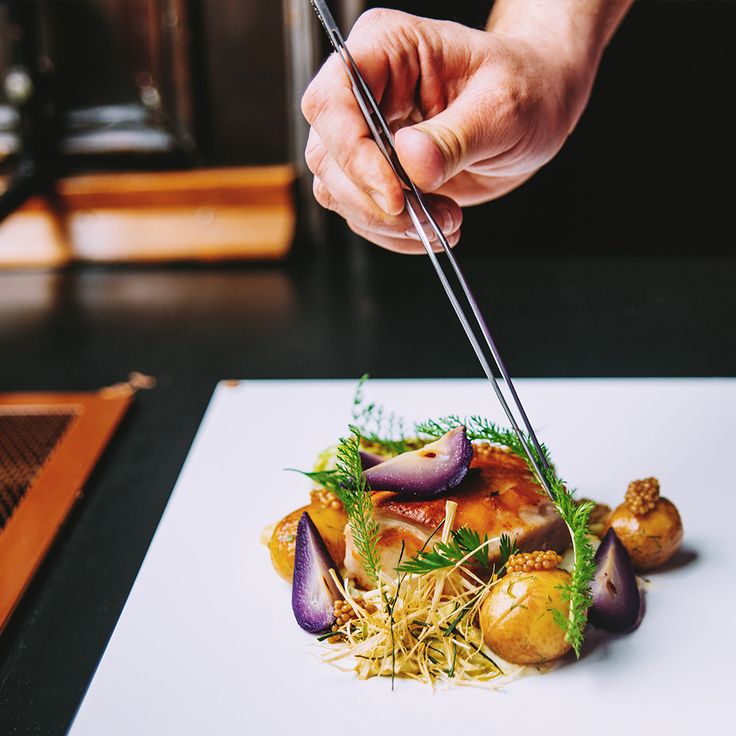 a person chopping up food on top of a white plate with chopsticks