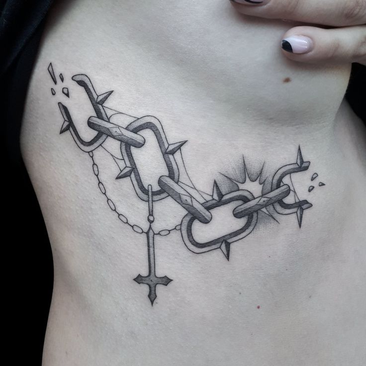 a woman's stomach with a chain and cross tattoo on her side ribcage