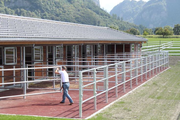 a man standing on top of a field next to a metal rail near a building