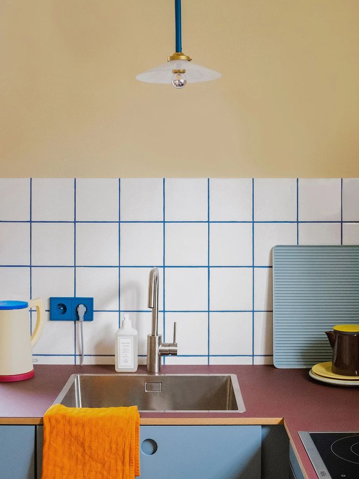 a kitchen with blue and white tiles on the wall, sink and stove top oven