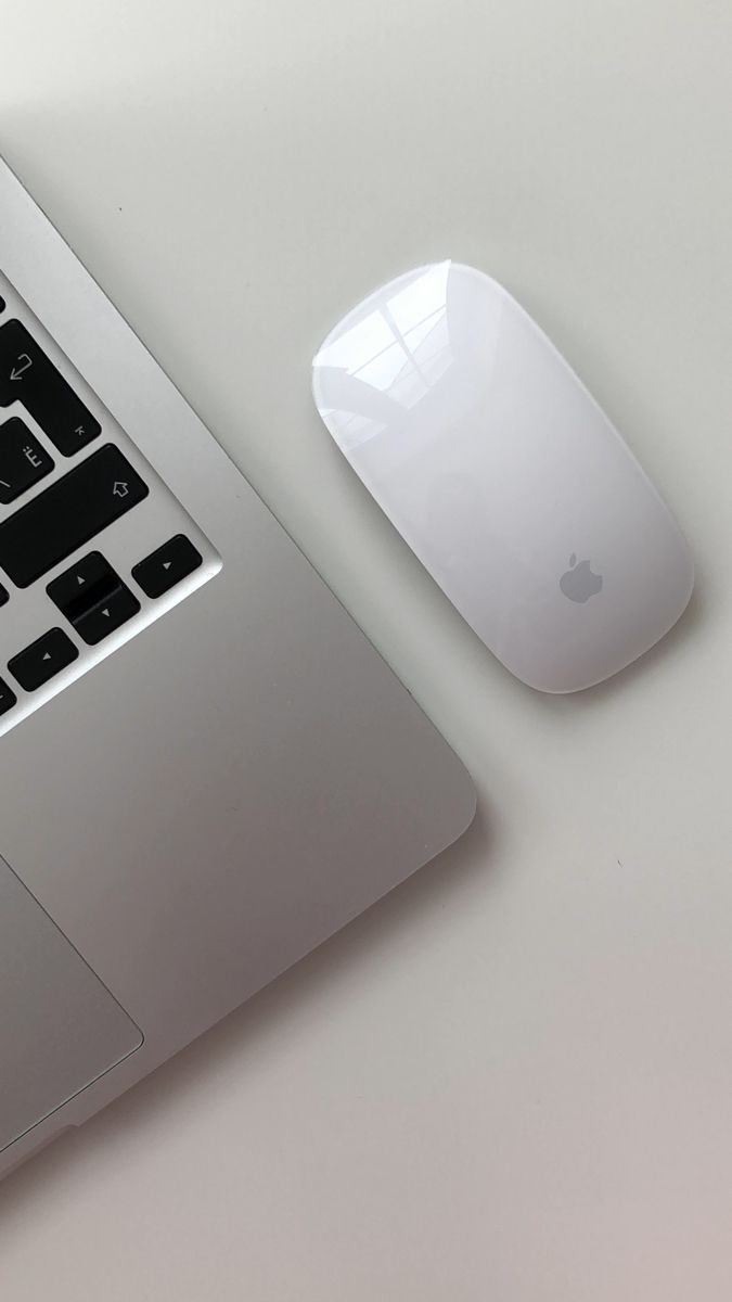 an apple mouse sitting on top of a laptop computer