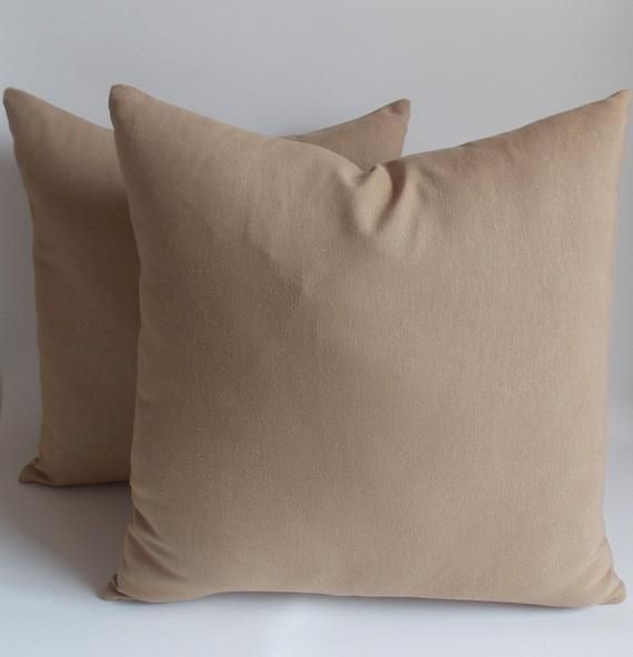 two tan pillows sitting next to each other