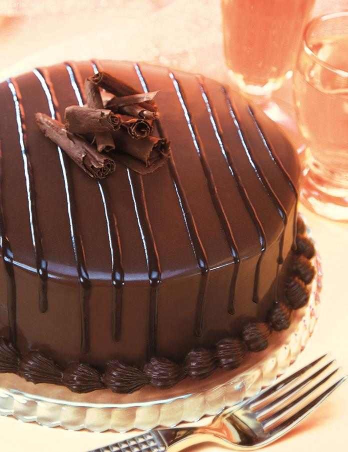 a chocolate cake sitting on top of a glass plate next to a knife and fork