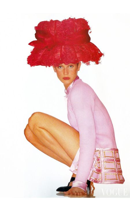 a woman with red hair sitting on top of a white floor wearing high heels and a pink shirt