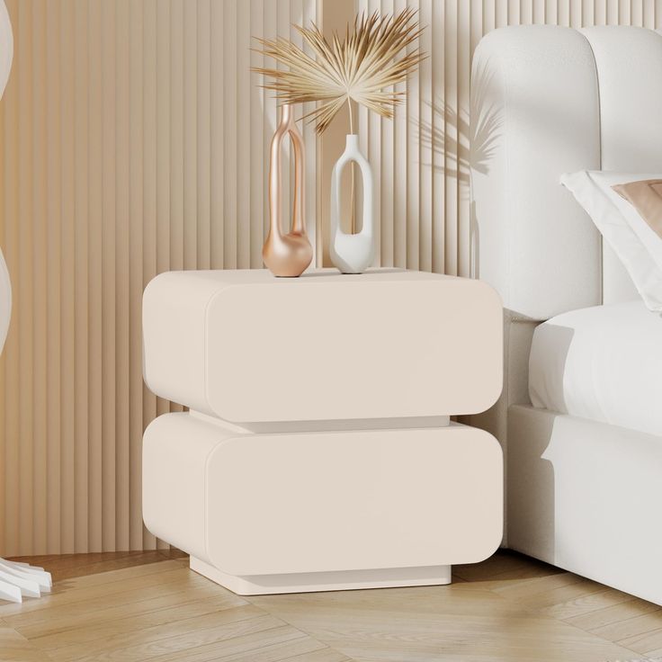 two white vases sitting on top of each other next to a bed