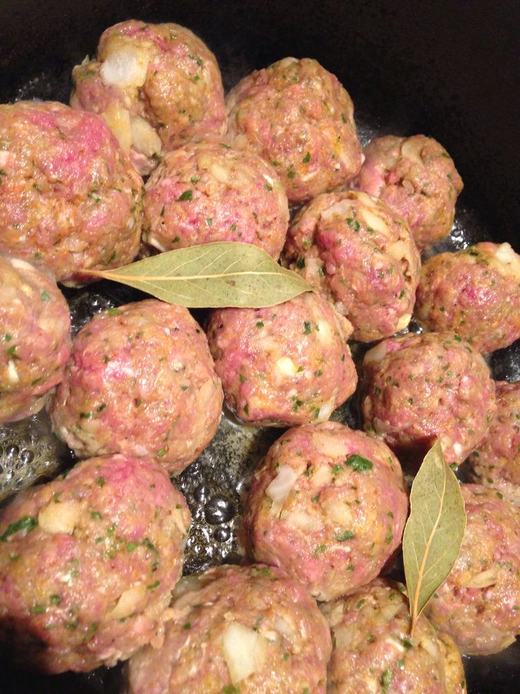 meatballs with herbs and spices cooking in a pan on the stove top, ready to be cooked