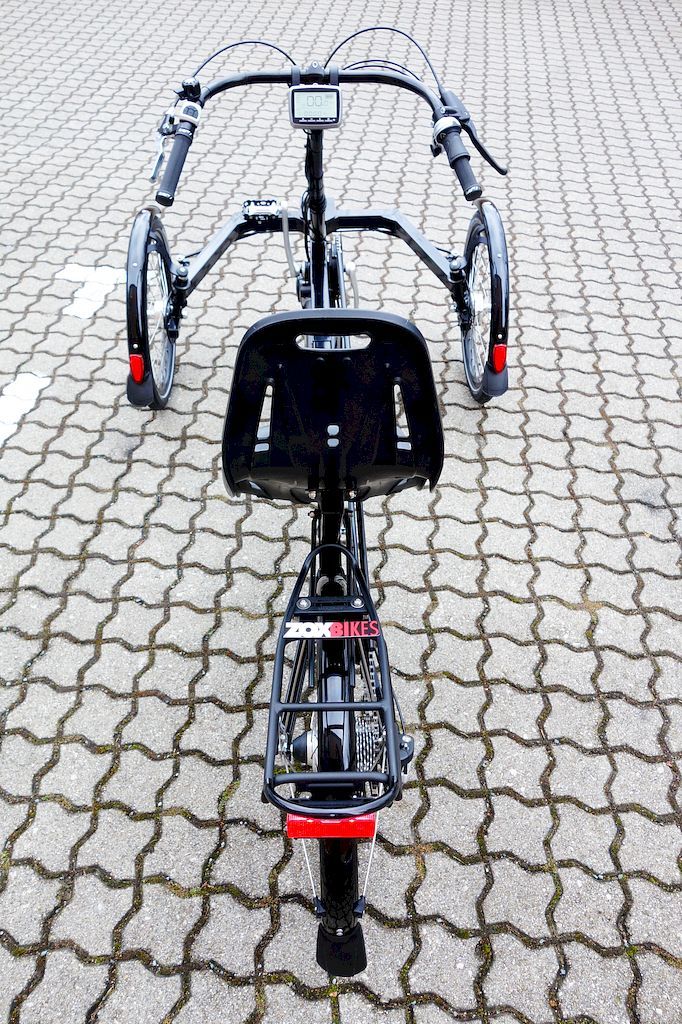 the front end of a bicycle parked on a cobblestone street with no one around it