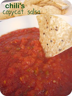 a tortilla chip being dipped into a bowl of chili sauce with a cracker