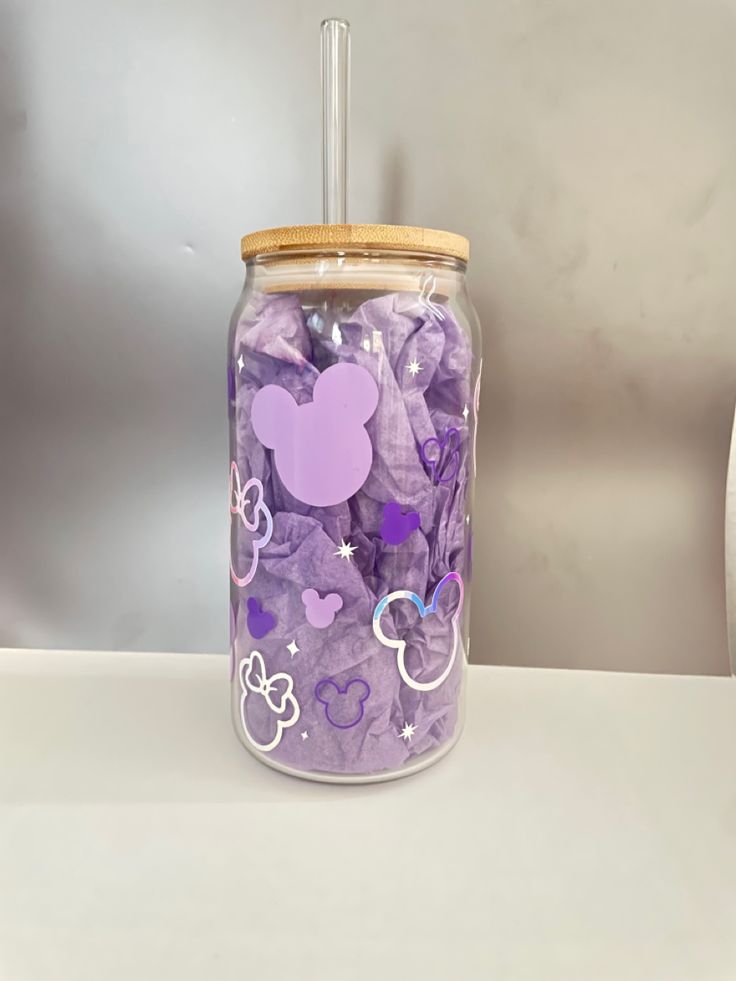 a glass jar filled with lots of purple and white confetti next to a wall