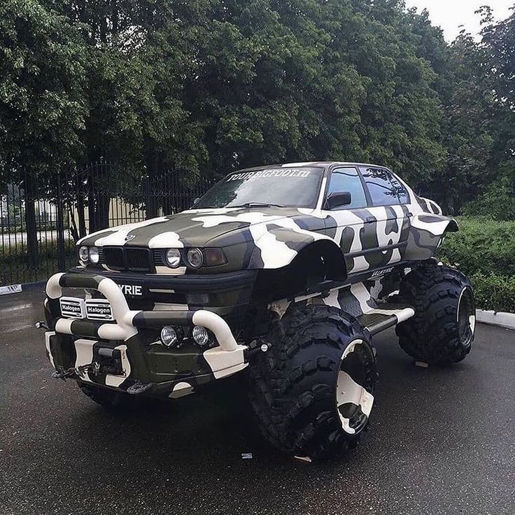 a camouflaged car is parked on the street in front of some trees and bushes