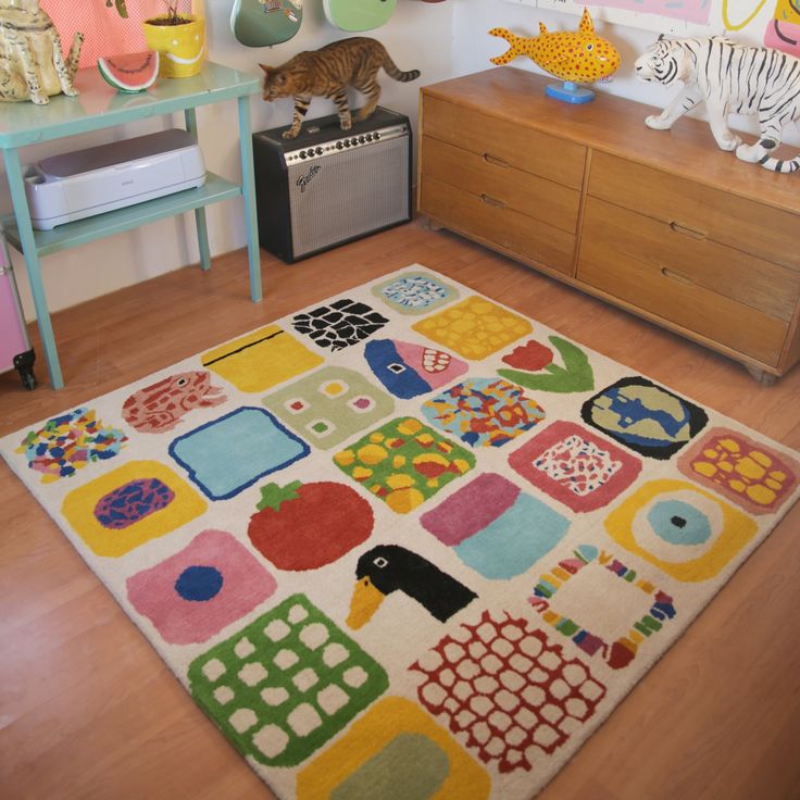 a colorful rug is in the middle of a room with toys and other items on the wall