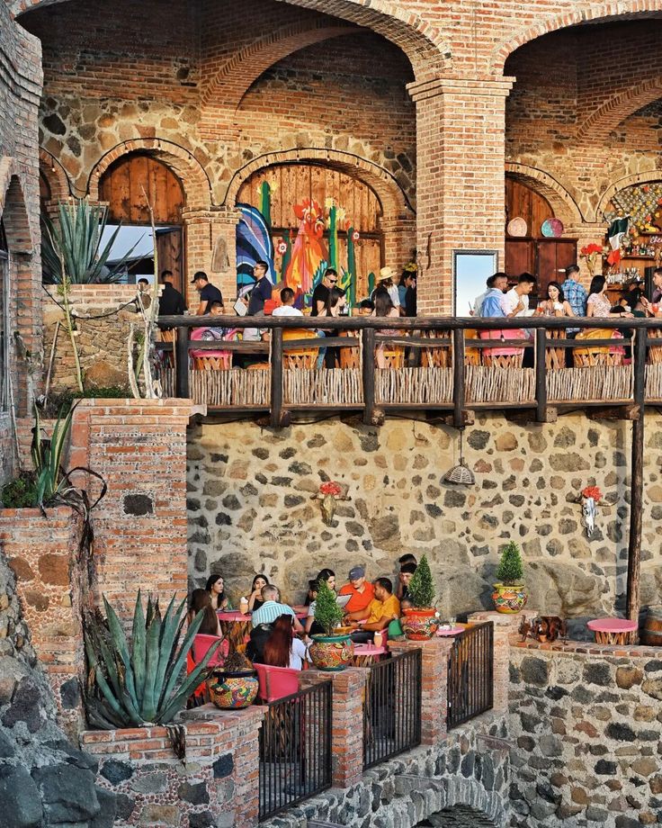 people are sitting on the balconies in an old building with brick walls and arched doorways