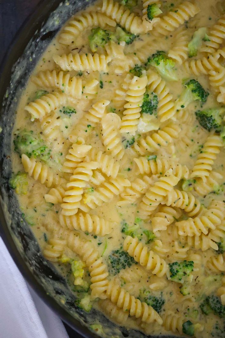 a pot filled with pasta and broccoli covered in cheese