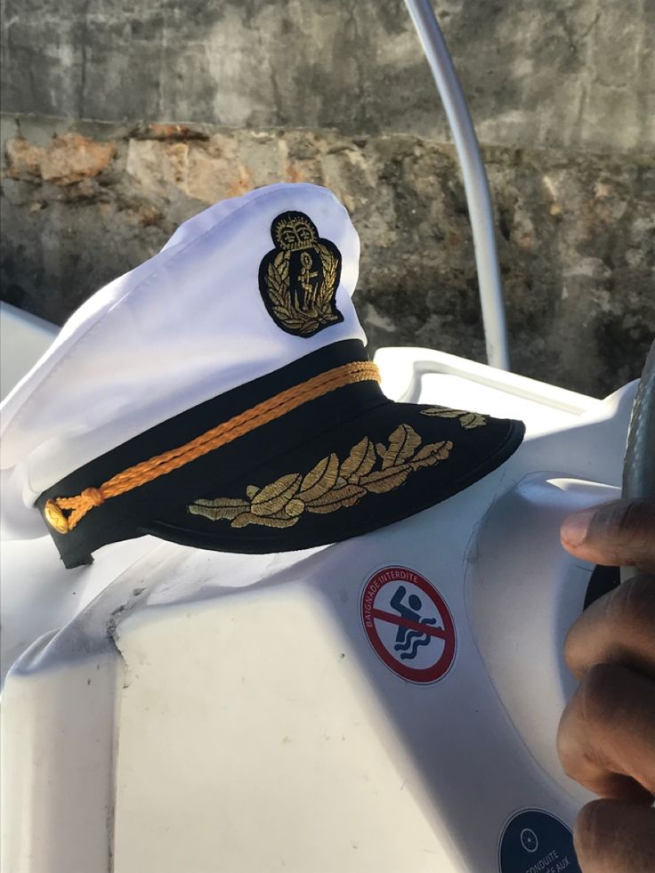 the captain's hat is on top of the steering wheel of a small boat