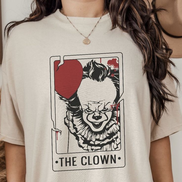 Step Into The Spookiest Season Of The Year With Our Halloween Red Fright Night The Clown Tarot Card T Shirt, The Perfect Blend Of Comfort And Eerie Style. Each Tee Is Meticulously Designed, Featuring The Iconic Horror Character The Clown Portrayed In A Uniquely Mystic Style On A Tarot Card. Available In A Variety Of Eerie Colors And A Broad Range Of Sizes. Perfect Blend Of Comfort And Halloween Spirit. A Great Conversation Starter For Any Horror Fan. A Stylish, Cozy Tribute To The Season's Chill Mystic Style, Desert Bloom, Halloween Pink, White Collared Shirt, The Clown, Fright Night, Tiger T Shirt, Ladies Tee Shirts, Tarot Card