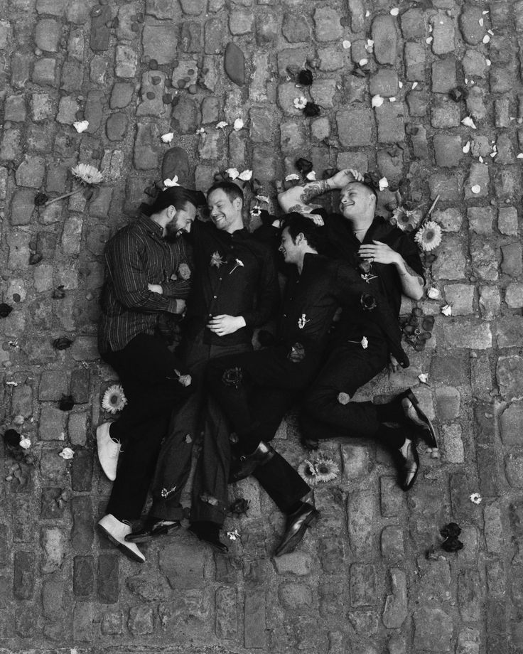 black and white photograph of three men laying on the ground with their arms around each other