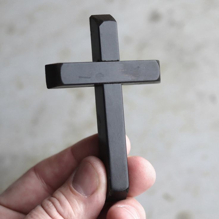 a person holding a black cross in their hand