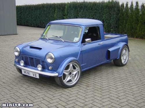 an old blue pick up truck parked in front of a hedge