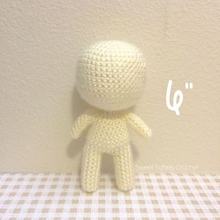 a crocheted doll sitting on top of a checkered tablecloth covered table