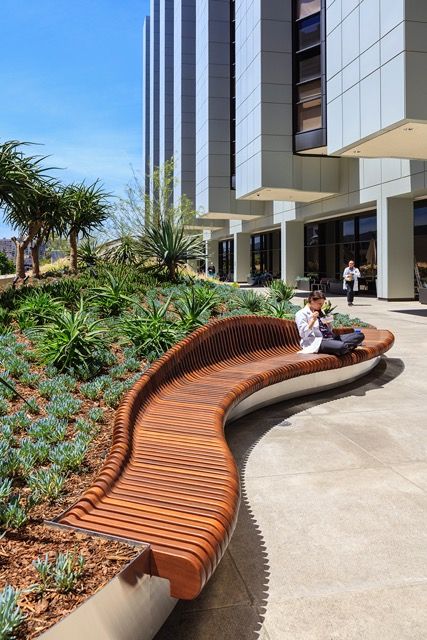 two people sitting on a bench in the middle of a walkway next to a building