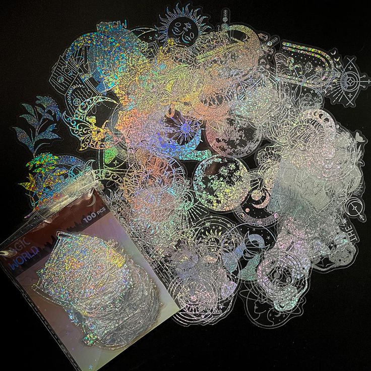 a pile of holographics on a black background with a cup of coffee next to it