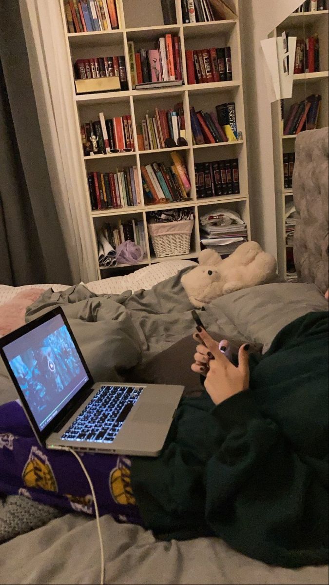 a person sitting on a bed with a laptop and cell phone in front of them