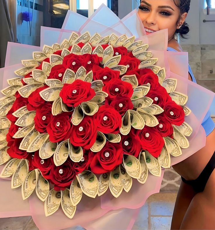 a woman holding a bouquet of red roses and dollar bills in front of her face