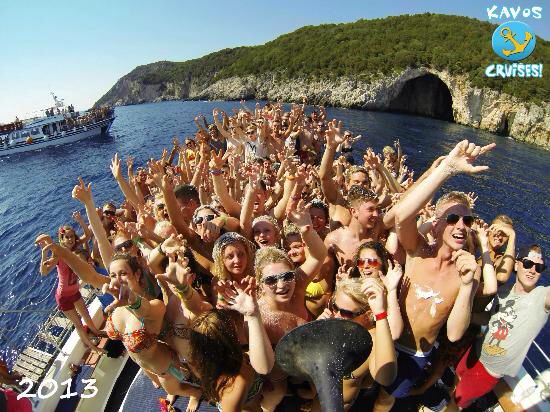 a group of people standing on top of a boat in the ocean with their hands up