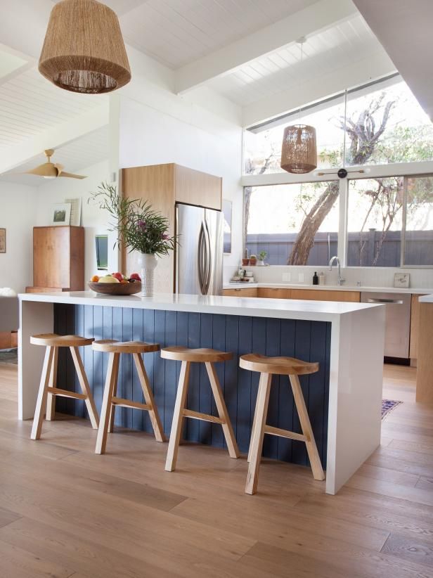 a kitchen with three stools next to an island in front of a window and potted plant on the counter