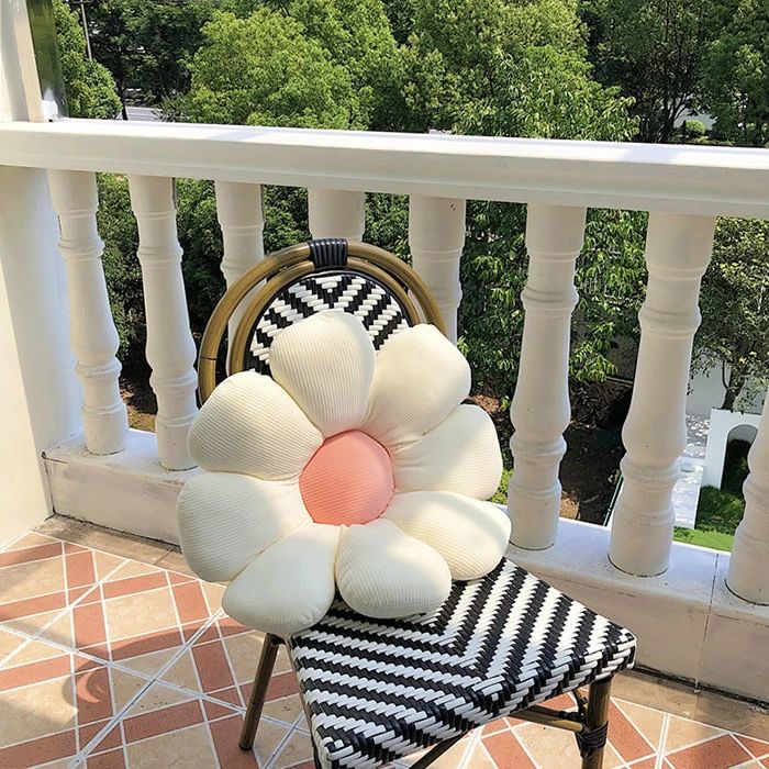 a white flower sitting on top of a black and white chair next to a balcony