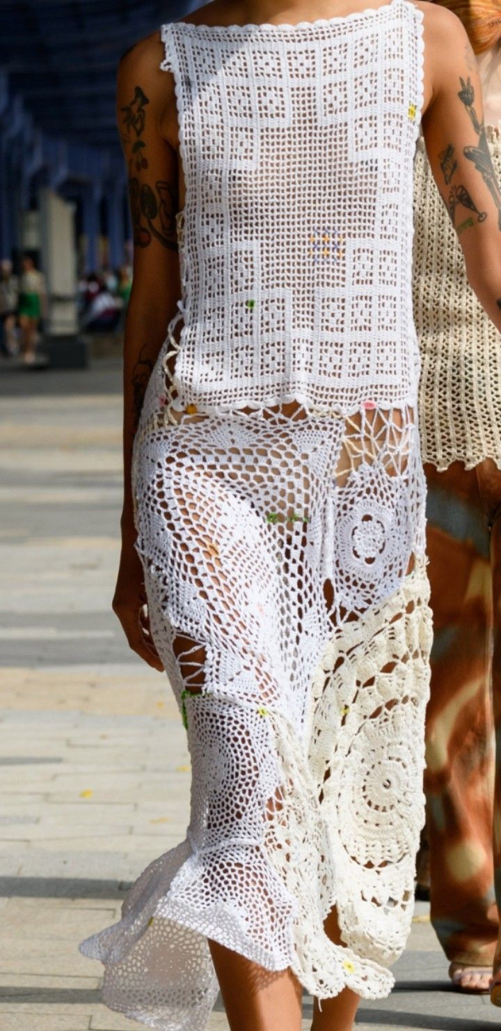 a woman walking down the street in a white crochet dress and matching sandals