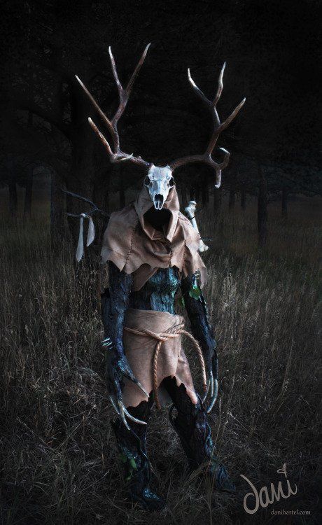 a man dressed up as a deer with antlers on his head in the grass