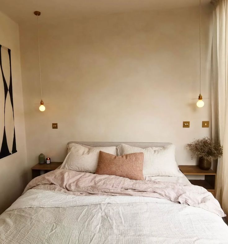 a bed with white sheets and pillows in a bedroom next to a wall mounted light fixture