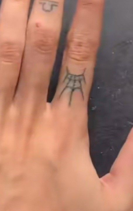 a person's hand with a small tattoo on the middle finger and an upside down ring