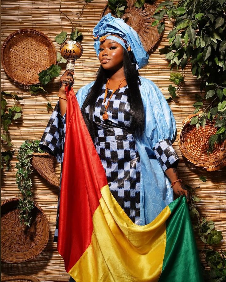 a woman holding an african flag in front of a wall with plants and baskets on it