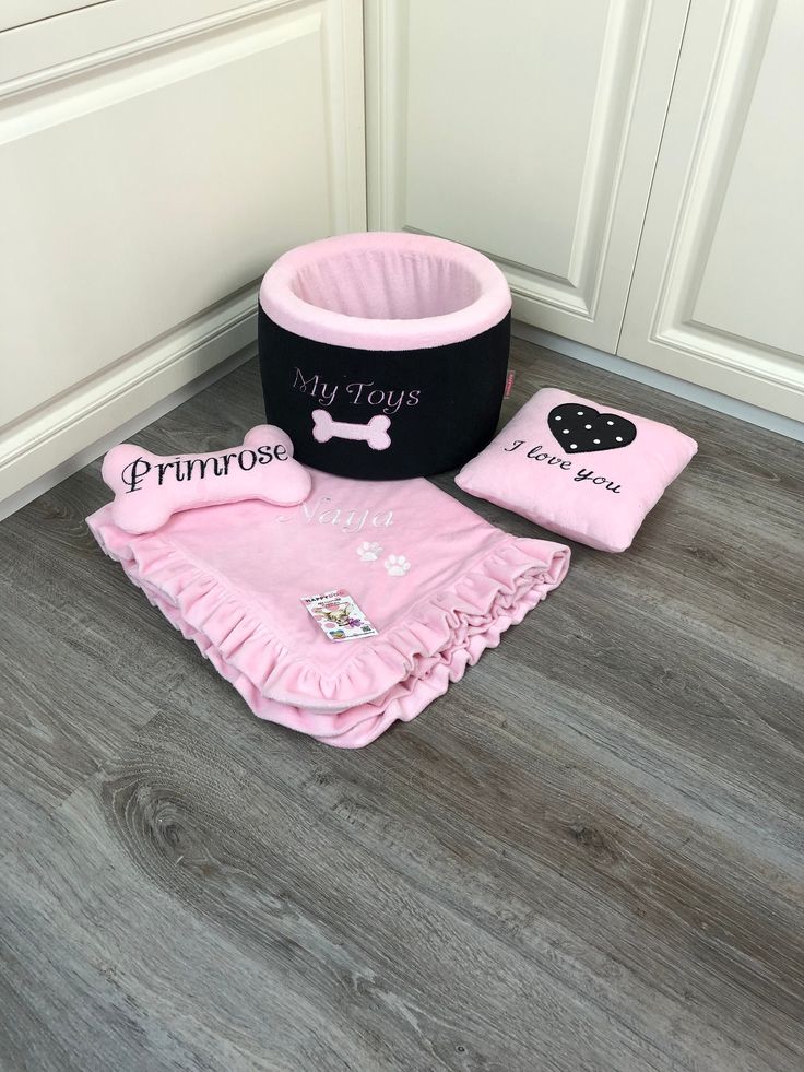 a pink and black dog bed next to its owner's personal items on the floor