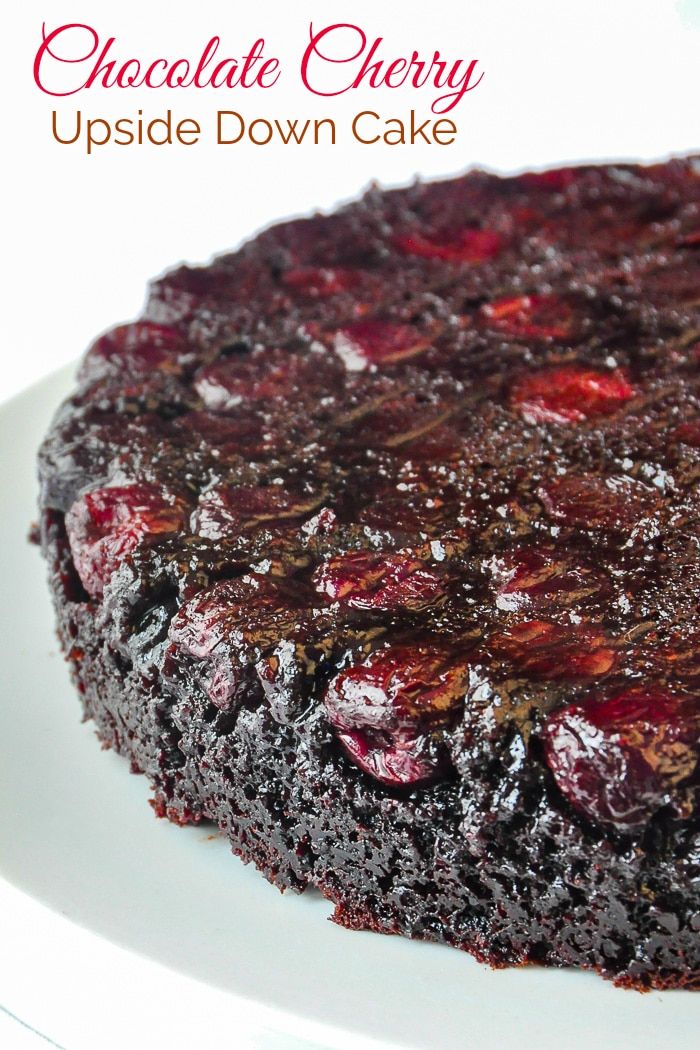 a chocolate cherry upside down cake on a white plate with the words, chocolate cherry upside down cake